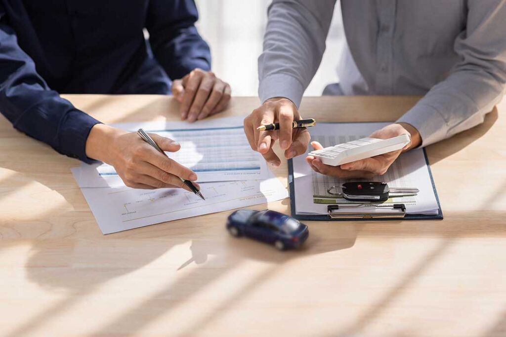 Family members review a life insurance policy and funeral expense documents at a kitchen table.