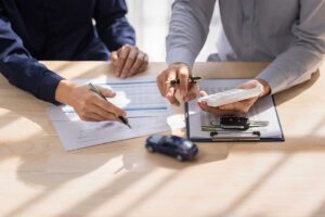 Family members review a life insurance policy and funeral expense documents at a kitchen table.