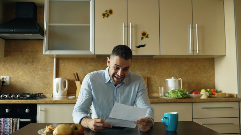 A homeowner reviews renewal papers beside a calculator and house keys at a kitchen table.